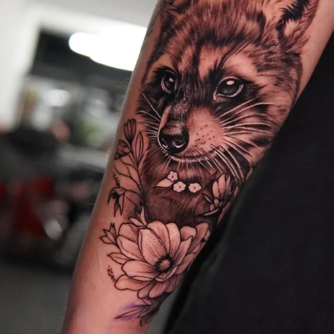 Black and Grey Waschbär mit Blumen am Unterarm – Andres, Prime Ink Bremen