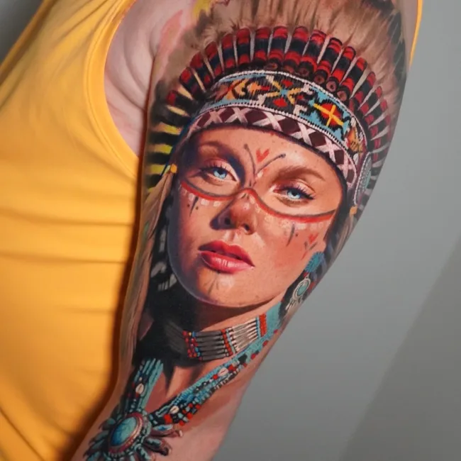 Farbtattoo Frau mit Federschmuck am Oberarm – Kate, Prime Ink Bremen
